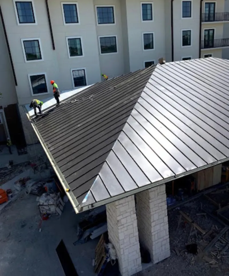 Crew installing standing seam metal roof panels on a commercial project in Woodfield